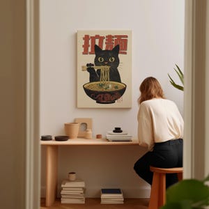 May include: A black cat with a bowl of ramen in front of it. The cat is holding chopsticks and eating the noodles. The image is in a vintage style with Japanese text that says "Ramen Cat".