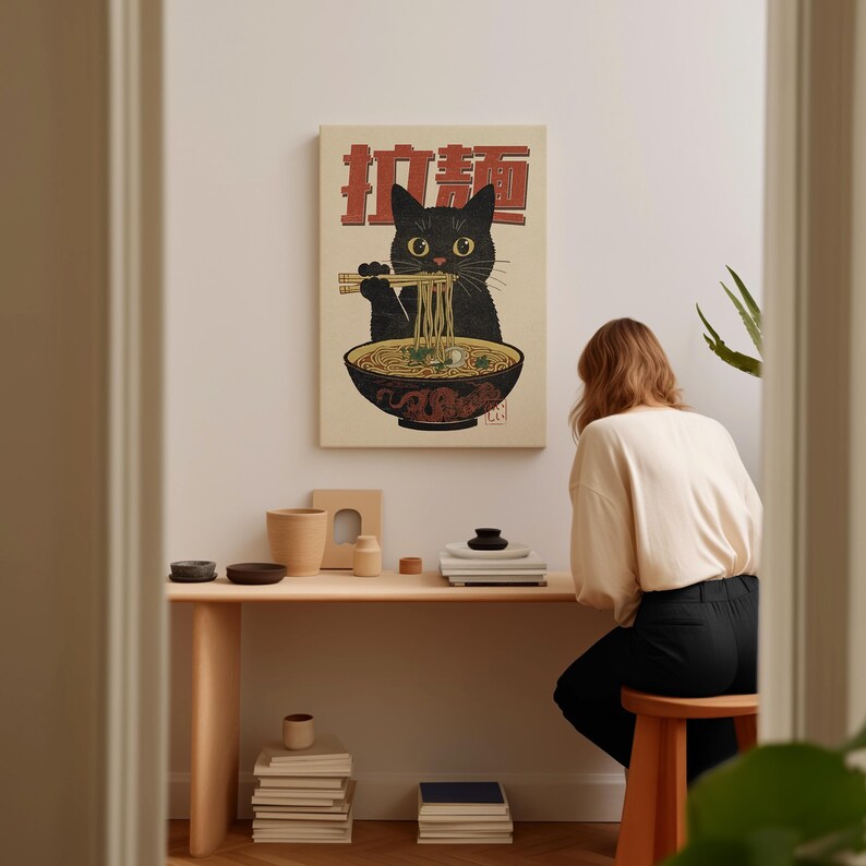 May include: A black cat with a bowl of ramen in front of it. The cat is holding chopsticks and eating the noodles. The image is in a vintage style with Japanese text that says "Ramen Cat".