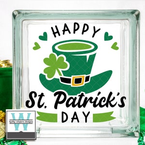 May include: A glass block with a green leprechaun hat and shamrock design. The text "Happy St. Patrick's Day" is written in black lettering.