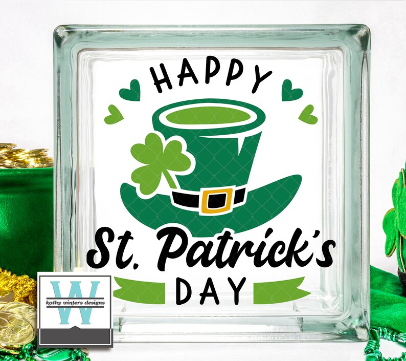 May include: A glass block with a green leprechaun hat and shamrock design. The text "Happy St. Patrick's Day" is written in black lettering.