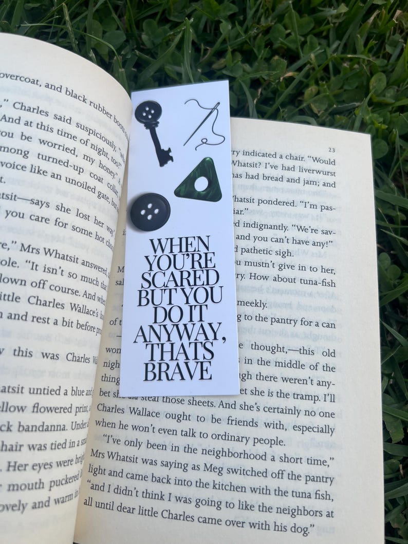 May include: A bookmark with a black and white quote that reads "When you're scared but you do it anyway, that's brave." The bookmark is decorated with a key, a needle and thread, and three green buttons.