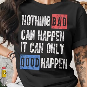 May include: Black t-shirt with the text "NOTHING BAD CAN HAPPEN IT CAN ONLY GOOD HAPPEN" in white, with the words "BAD" in a red box and "GOOD" in a blue box. The shirt has short sleeves.