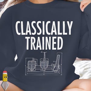Puede incluir: Sudadera azul marino con el texto blanco "CLASSICALLY TRAINED". Debajo, una ilustración estilo plano de pedales de coche.