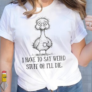 Peut inclure: T-shirt blanc avec un dessin d'oiseau de dessin animé tenant une tasse. L'oiseau a de grands yeux et un long cou. Le texte "I HAVE TO SAY WEIRD STUFF OR I'LL DIE" est imprimé en noir en dessous. Le t-shirt est noué à la taille.