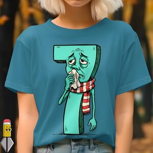 Peut inclure: T-shirt bleu sarcelle avec une illustration de dessin animé du chiffre sept. Le chiffre a une expression triste, se mouche avec un mouchoir et porte une écharpe à rayures rouges et blanches. Le t-shirt est de couleur sarcelle unie.