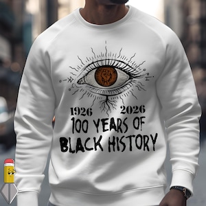 May include: White sweatshirt with a graphic eye design featuring a brown fist within the iris. The text reads "1926 2026 100 YEARS OF BLACK HISTORY" in black lettering. The design includes radiating lines and symbols.