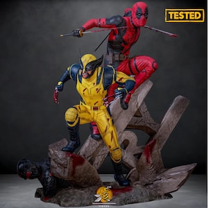 May include: A detailed figurine featuring Wolverine in a yellow and blue suit, and Deadpool in a red and black suit. Both characters are posed in action, with Wolverine's claws extended and Deadpool holding swords. The base is a rocky structure with blood splatter.