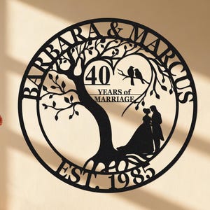 Könnte beinhalten: Schwarze Metall-Wandkunst mit einem Baumdesign, den Namen "Barbara & Marcus" am Rand und dem Text "40 YEARS of MARRIAGE" und "EST 1985". Silhouetten eines Paares und Vögel sind ebenfalls enthalten.