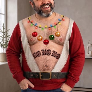 Peut inclure: Un sweat-shirt rouge à manches longues avec un imprimé représentant un torse nu poilu, orné d'une guirlande de lumières de Noël colorées et de boules suspendues. Le motif inclut une ceinture noire et l'inscription HO HO HO.