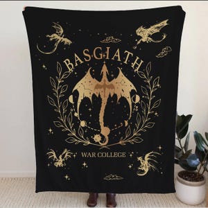 May include: Black blanket with a gold dragon design. The blanket features the text "BASGIATH WAR COLLEGE" and several gold dragons. The central dragon is surrounded by a gold wreath with celestial elements.