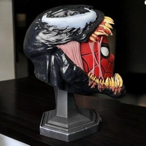 Puede incluir: Un busto de Venom negro y rojo con dientes afilados y una escultura detallada. El busto est&aacute; sobre una base negra y es una figura coleccionable.