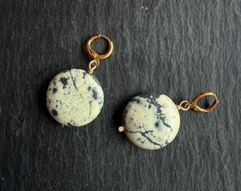 May include: A pair of earrings featuring round, cream-colored stone pendants with dark gray, web-like crackle patterns. Each pendant is suspended from a small, polished gold-tone metal hoop clasp, creating a simple and cohesive jewelry set.
