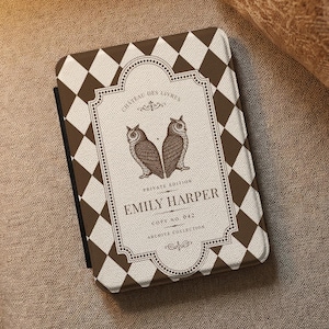Könnte beinhalten: Eine rechteckige E-Reader-Hülle mit einem braun-weißen Rautenmuster. In der Mitte befindet sich ein dekoratives Etikett mit dem Text CHATEAU DES LIVRES, PRIVATE EDITION, EMILY HARPER, COPY NO. 042, ARCHIVE COLLECTION sowie zwei Eulen.