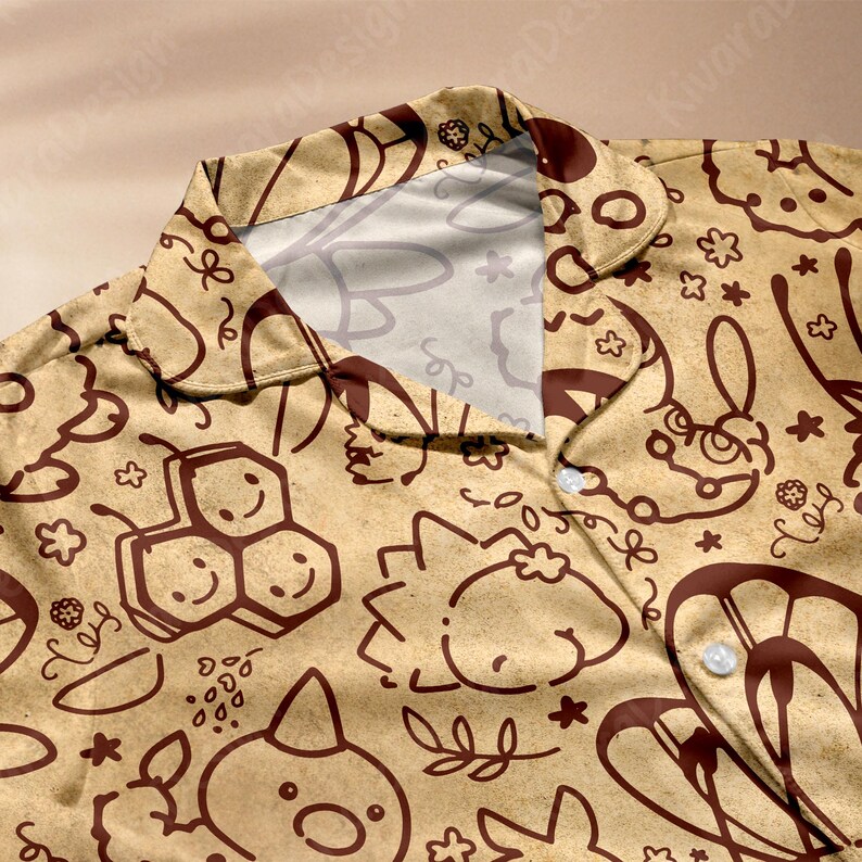 K&ouml;nnte beinhalten: Beigefarbenes Hemd mit Kn&ouml;pfen und einem sich wiederholenden Muster aus braunen Cartoon-Illustrationen, darunter Bienen, Hasen und Blumen. Das Hemd hat einen klassischen Kragen und wei&szlig;e Kn&ouml;pfe. Der Stoff wirkt weich und leicht.