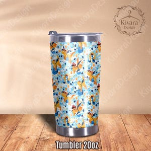 K&ouml;nnte beinhalten: Ein 20 oz (ca. 590 ml) Becher mit einem verspielten Muster aus Cartoon-Drachen, Spielkarten und Sternen auf hellblauem Hintergrund. Der Becher hat einen silbernen Deckel und Boden. Der Text "Tumbler 20oz" steht unten.