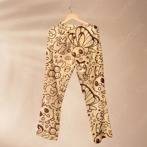 K&ouml;nnte beinhalten: Beige Schlafanzughose mit einem sich wiederholenden Muster aus Cartoon-Insekten, Blumen und Sternen in Dunkelbraun. Die Hose h&auml;ngt an einem Holzb&uuml;gel vor einem neutralen Hintergrund. Das Design umfasst Schmetterlinge, Bienen und andere skurrile Kreaturen.