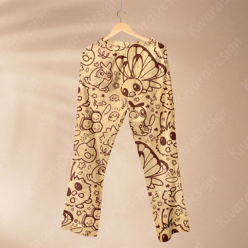 K&ouml;nnte beinhalten: Beige Schlafanzughose mit einem sich wiederholenden Muster aus Cartoon-Insekten, Blumen und Sternen in Dunkelbraun. Die Hose h&auml;ngt an einem Holzb&uuml;gel vor einem neutralen Hintergrund. Das Design umfasst Schmetterlinge, Bienen und andere skurrile Kreaturen.