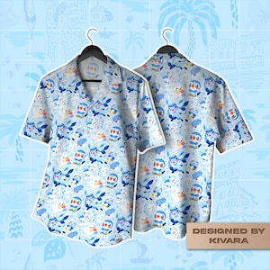 Puede incluir: Una camisa de manga corta con botones y un estampado integral en azul claro de personajes de pingüinos de dibujos animados. La camisa tiene cuello y se muestra en dos perchas negras. Una etiqueta rectangular dice DESIGNED BY KIVARA.