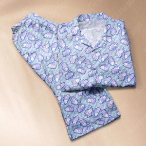 以下が含まれることがあります： 紫と白の漫画のハリネズミの繰り返し模様が特徴の、水色のパジャマセット。 パジャマには、ボタンダウンのトップスとマッチするパンツが含まれています。 生地は微妙なストライプのデザインです。