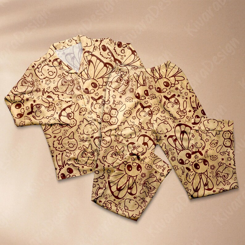 K&ouml;nnte beinhalten: Beigefarbenes Pyjama-Set mit einem sich wiederholenden Muster aus braunen Cartoon-Kreaturen. Das Set besteht aus einem Oberteil mit Kn&ouml;pfen und Kragen sowie einer langen Hose. Der Stoff hat ein Vintage-Aussehen.