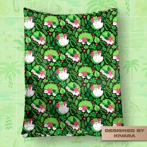 Op de afbeelding: Een groene deken met een herhalend patroon van witte, egelachtige wezens met groene en roze bloemaccenten, omringd door groene bladeren en rode bessen. De deken heeft een donkergroene achtergrond en de tekst "DESIGNED BY KIVARA".