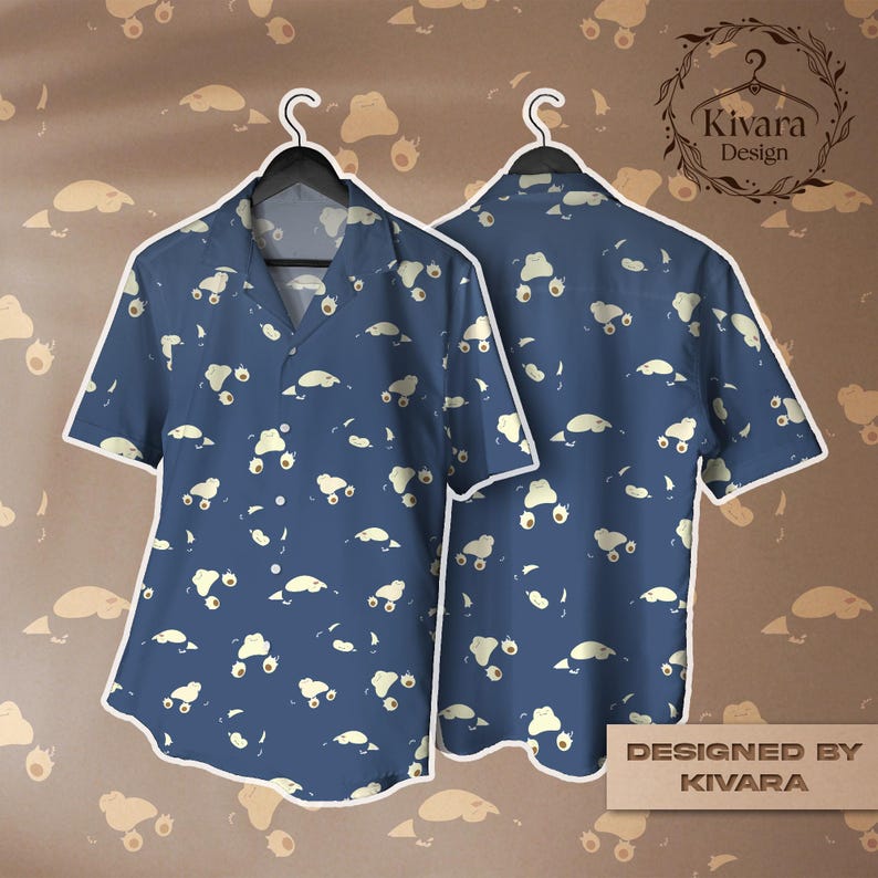 May include: A short-sleeved button-down shirt in a deep blue colour featuring an all-over pattern of small, light-coloured, amorphous blob-like figures. The shirt has a classic collar and a front button closure. The text KIVARA DESIGN is visible.
