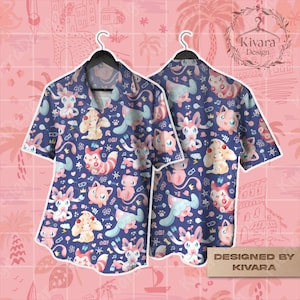 Puede incluir: Dos camisas de manga corta con botones con un fondo azul marino y un patrón repetido de personajes de dibujos animados en rosa, blanco y azul. Las camisas cuelgan de perchas negras. Las palabras "DESIGNED BY KIVARA" están en la esquina inferior derecha.