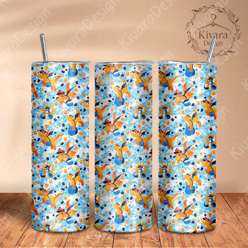 K&ouml;nnte beinhalten: Drei Edelstahlbecher mit einem skurrilen Muster aus orangefarbenen Drachen, die H&uuml;te tragen und Musikinstrumente spielen, auf hellblauem Hintergrund. Das Design umfasst Sterne und Spielkarten. Jeder Becher hat einen silbernen Strohhalm.
