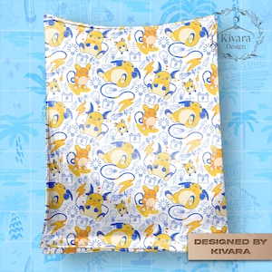 Op de afbeelding: Witte deken met een herhaald patroon van gele en oranje stripfiguren, blauwe bliksemschichten, gloeilampen en batterijen. Het ontwerp is blauw omlijnd. De deken heeft een glanzende, reflecterende uitstraling. De tekst "Designed by KIVARA" is zichtbaar.