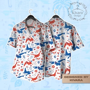 Può includere: Una camicia a maniche corte con bottoni, caratterizzata da una base bianca con un motivo ripetitivo di creature stilizzate rosse e blu simili a uccelli, intervallate da piccoli fiori rossi e rametti blu con foglie.