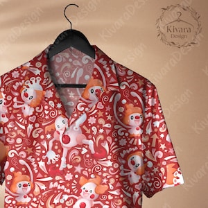 Puede incluir: Camisa roja con botones con un patrón repetido de personajes de dibujos animados, corazones, estrellas y espirales. Los personajes tienen pelo naranja y caras blancas. La camisa está colgada de una percha negra.