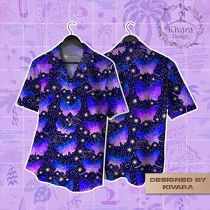 Può includere: Una camicia a maniche corte con sfondo blu scuro e un motivo ripetuto di farfalle viola e blu. La camicia è esposta su una gruccia, mostrando i disegni anteriori e posteriori. Le parole "DESIGNED BY KIVARA" sono stampate su un rettangolo dorato.