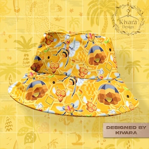 Peut inclure: Chapeau bob jaune avec un motif répété d'abeilles, de nids d'abeilles et de formes géométriques. Le chapeau a un large bord et est étiqueté "Designed by KIVARA". Le fond est une grille jaune avec des dessins de palmiers et de bâtiments.
