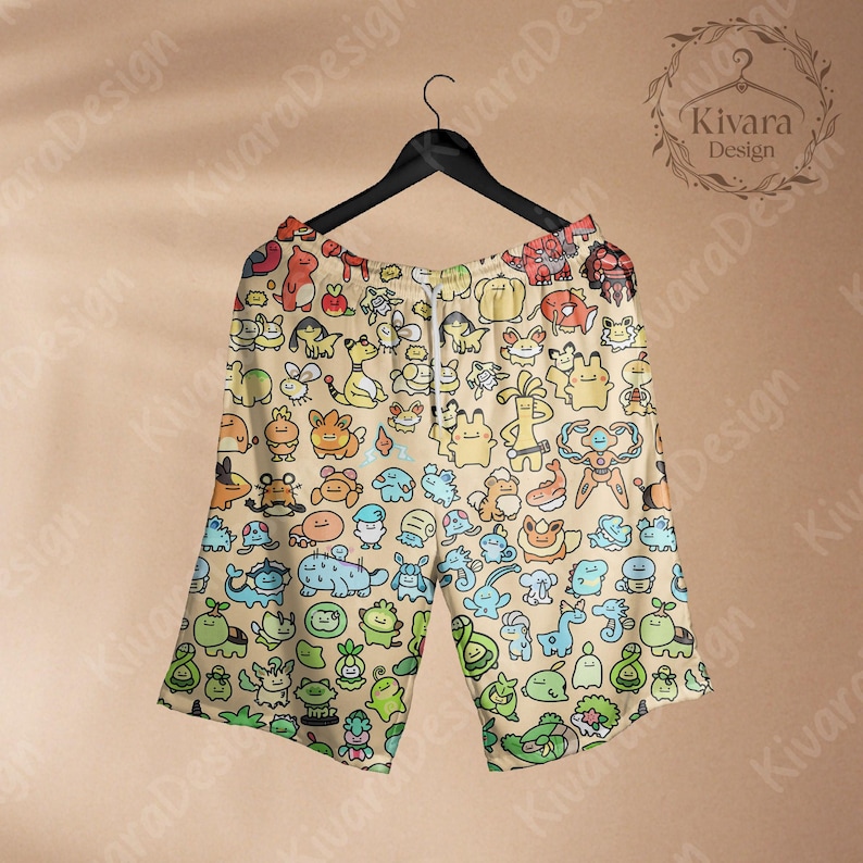May include: Tan shorts with a repeating pattern of colorful cartoon characters. The shorts have a drawstring waist and are hanging on a black hanger. The shorts are a light tan color with a variety of cartoon characters in shades of blue, green, orange, and yellow.