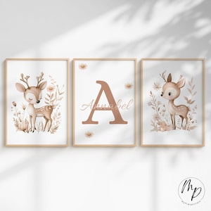 May include: Three framed art prints featuring a woodland theme. The prints include a deer illustration, a large letter "A" with the name "Annabel", and another deer illustration. The color palette is soft, with beige, brown, and white tones.