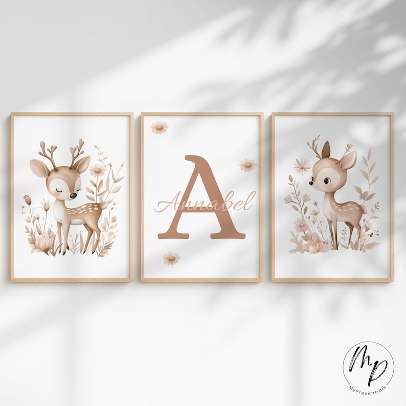 May include: Three framed art prints featuring a woodland theme. The prints include a deer illustration, a large letter "A" with the name "Annabel", and another deer illustration. The color palette is soft, with beige, brown, and white tones.