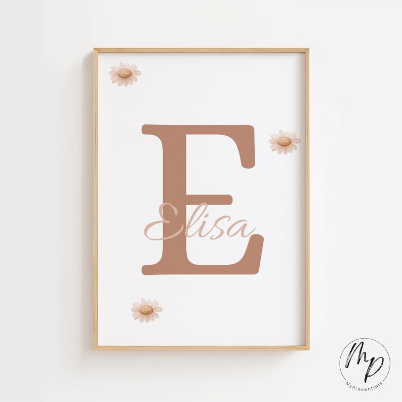 May include: A framed print featuring a large, brown letter "E" with the name "Elisa" in cursive script. The print is decorated with three daisy illustrations and has a light wood frame. The background is white.
