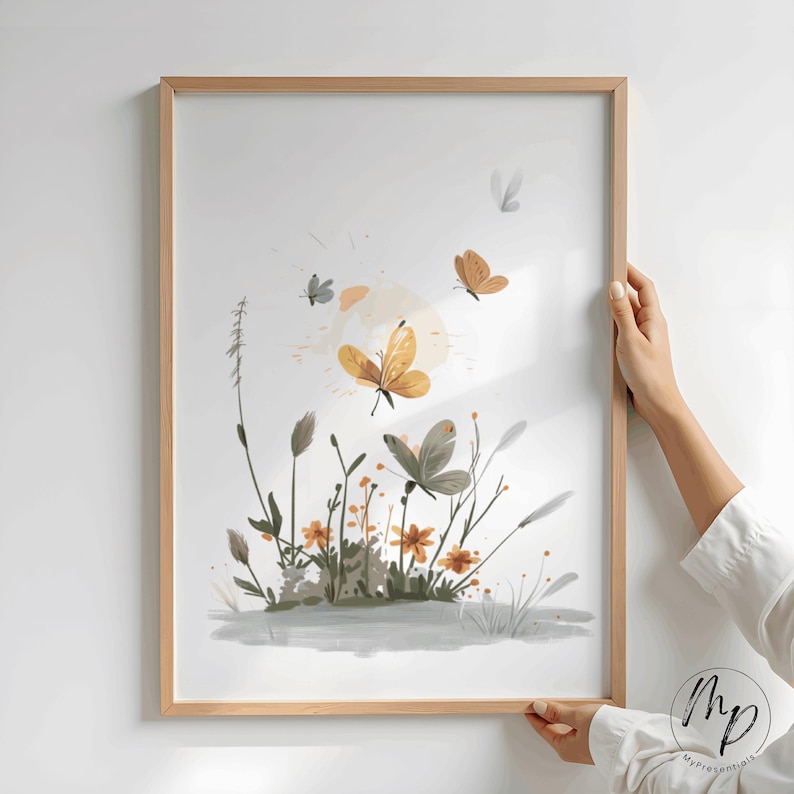 K&ouml;nnte beinhalten: Ein gerahmter Kunstdruck mit einer Aquarellillustration von Schmetterlingen und Wildblumen. Das Kunstwerk zeigt Schmetterlinge in Gold-, Braun- und Graut&ouml;nen, die &uuml;ber einem Feld aus orangefarbenen Blumen und gr&uuml;nem Laub schweben. Der Druck ist in einem hellbraunen Holzrahmen eingefasst.