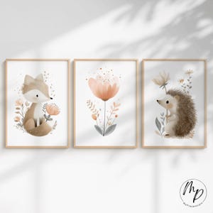 Puede incluir: Tres impresiones enmarcadas en acuarela con animales del bosque y elementos florales. Las impresiones incluyen un zorro, una flor grande y un erizo, todos en colores suaves y apagados. Los marcos son de un tono de madera clara.