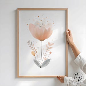 Puede incluir: Una impresi&oacute;n art&iacute;stica enmarcada que presenta una gran flor de color melocot&oacute;n con delicados p&eacute;talos y un tallo oscuro. La obra de arte incluye hojas m&aacute;s peque&ntilde;as de color melocot&oacute;n y gris y detalles dorados, todo sobre un fondo blanco.