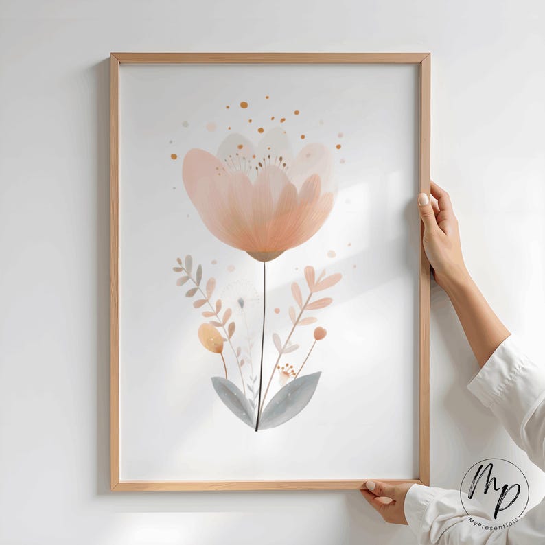 Puede incluir: Una impresi&oacute;n art&iacute;stica enmarcada que presenta una gran flor de color melocot&oacute;n con delicados p&eacute;talos y un tallo oscuro. La obra de arte incluye hojas m&aacute;s peque&ntilde;as de color melocot&oacute;n y gris y detalles dorados, todo sobre un fondo blanco.