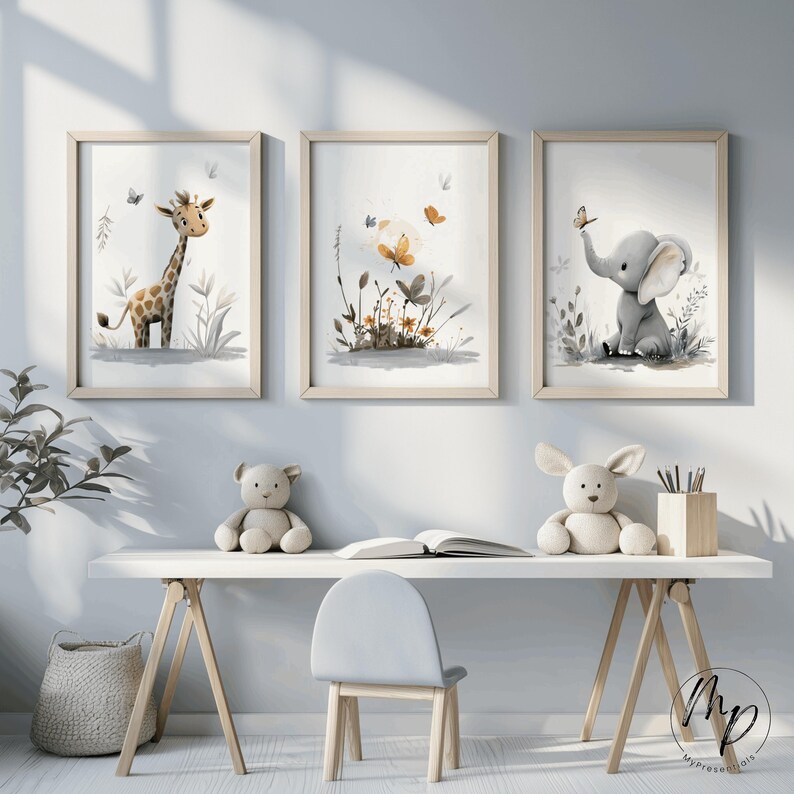 K&ouml;nnte beinhalten: Drei gerahmte Aquarelldrucke mit einer Giraffe, einem Blumenarrangement und einem Elefanten. Die Drucke haben helle Holzrahmen und weiche, neutrale Farben. Die Giraffe und der Elefant sind in einem skurrilen Stil gehalten, der f&uuml;r ein Kinderzimmer geeignet ist.