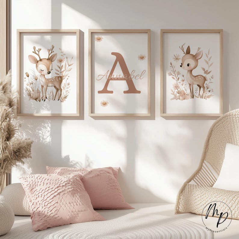 May include: Three framed art prints featuring a woodland theme. The prints include a deer illustration, a large letter "A" with the name "Annabel", and another deer illustration. The frames are light wood, and the artwork has a soft, neutral color palette.
