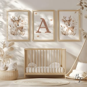 May include: Three framed nursery art prints featuring a watercolor deer illustration and a personalized print with the name "Annabel". The prints are in a light wood frame. A wooden crib, a woven basket, and a round rug complete the nursery decor.