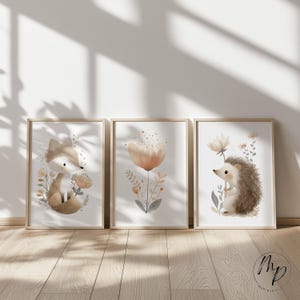 Puede incluir: Tres l&aacute;minas art&iacute;sticas enmarcadas con acuarelas que representan animales del bosque y elementos florales. Las l&aacute;minas incluyen un zorro, una flor y un erizo, todos en tonos suaves de marr&oacute;n, beige y melocot&oacute;n. Los marcos son de madera clara.