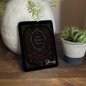 Pode incluir: Uma placa retangular preta com um design de moldura dourada ornamentada, rosas vermelhas e o texto Dark Romance Library e o nome Sherry em letra branca. A placa tem cantos arredondados e um design detalhado com detalhes florais.