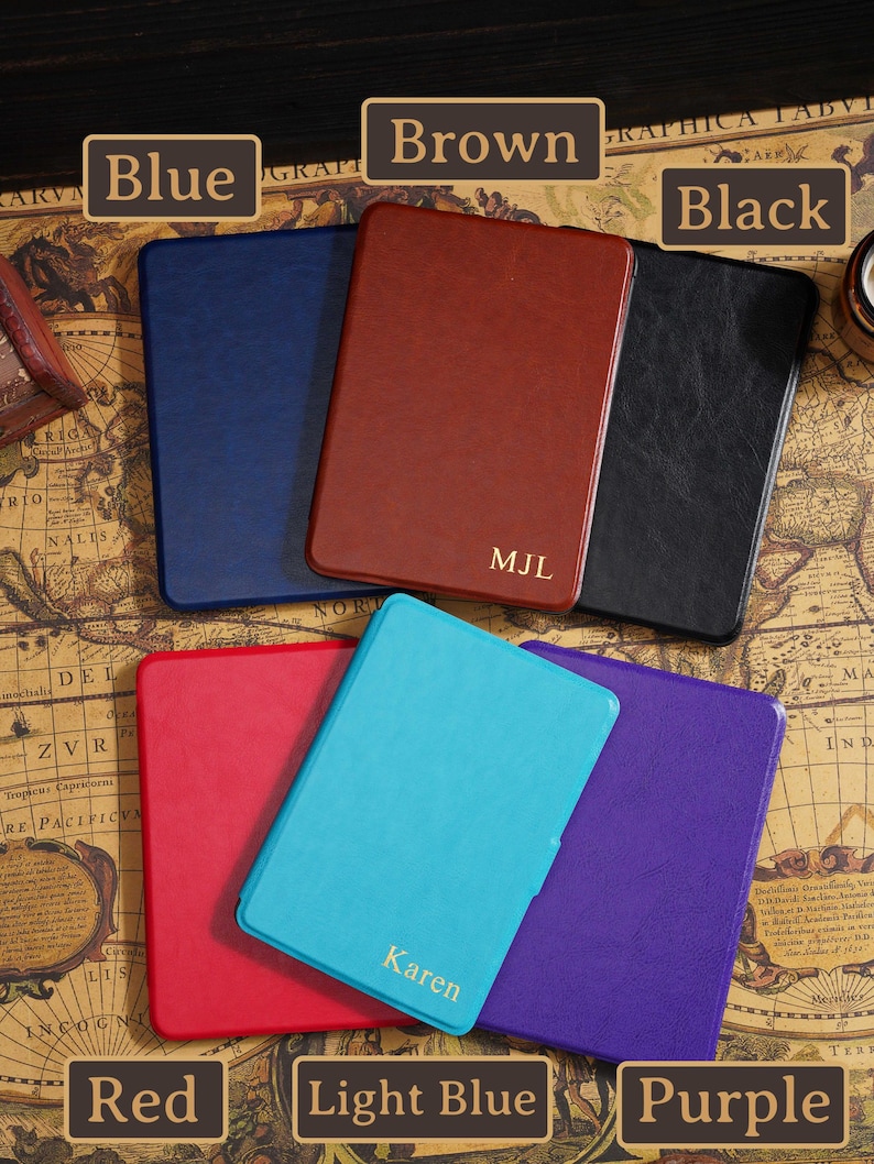 May include: A collection of leather-bound notebooks in various colors: blue, brown, black, red, light blue, and purple. The brown notebook is personalized with the initials "MJL", and the light blue notebook has the name "Karen".