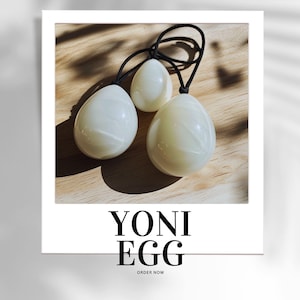 May include: Three white Yoni Eggs of different sizes, with black cords, on a wooden surface. The text "YONI EGG" and "ORDER NOW" is printed below the eggs.