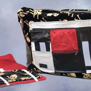 Może przedstawiać: Czarno-czerwona torba w stylu patchwork z motywem czaszki i skrzyżowanych kości. Torba ma dużą kieszeń zapinaną na zamek błyskawiczny z przodu i mniejszą kieszeń zapinaną na zamek błyskawiczny z boku. Torba jest wykonana z r&oacute;żnych materiał&oacute;w, w tym z aksamitu, sk&oacute;ry i bawełny.