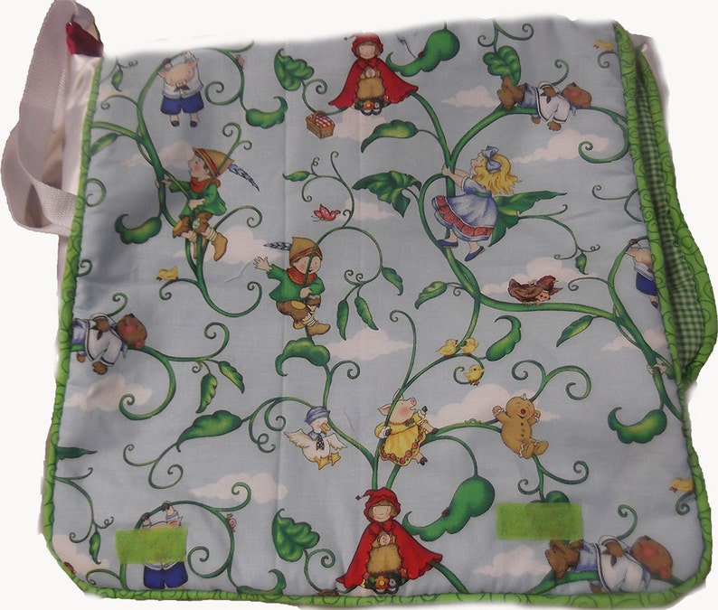 May include: A blue and green fabric tote bag with a whimsical design featuring characters climbing a beanstalk. The characters include a girl in a red hooded cloak, a girl in a blue dress, a boy in a green shirt, and a pig in a pink dress. The bag has a green and white trim.